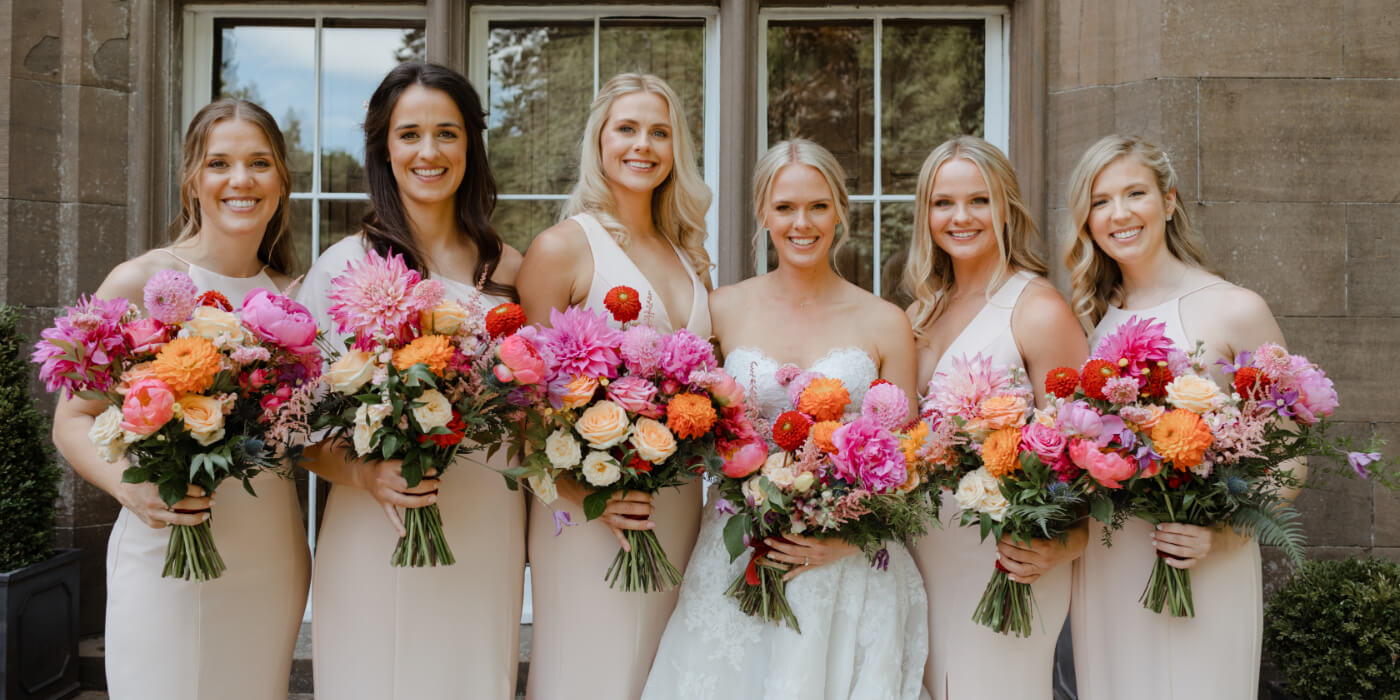 Bridesmaids all standing holding pink and white flowers
